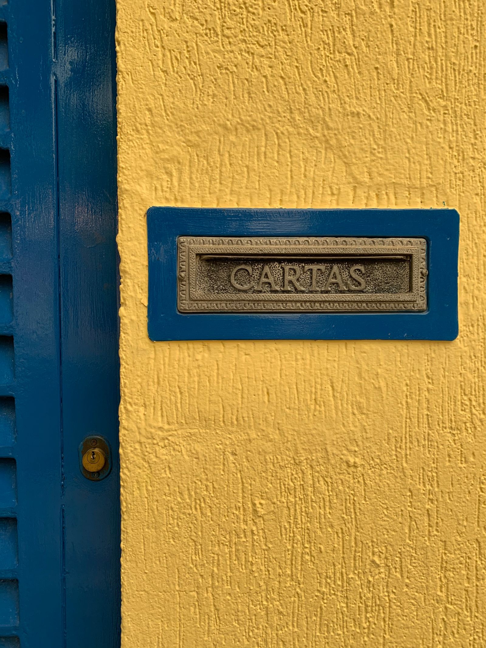 Ranura para cartas azul sobre una pared amarilla